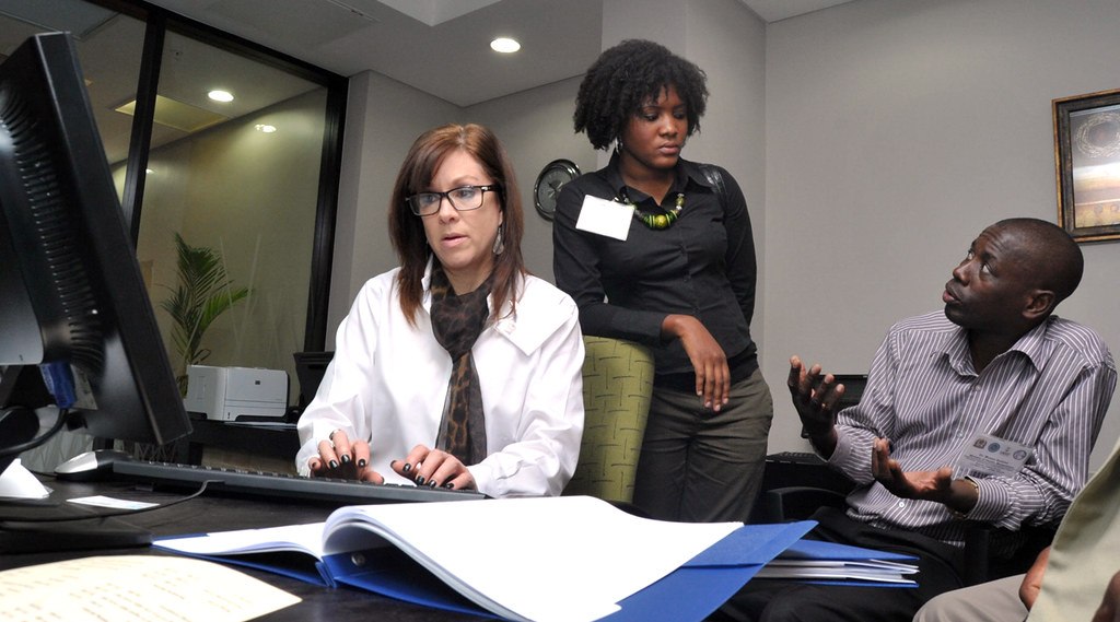 Manager and HR team reviewing ergonomics reporting notes and a workstation dashboard.
